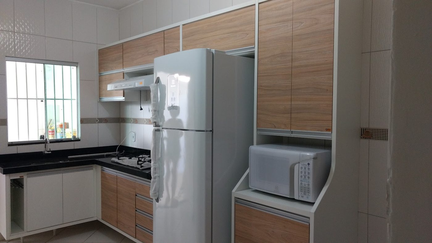 Cozinha planejada pela MENCA Móveis com armários em madeira e geladeira embutida