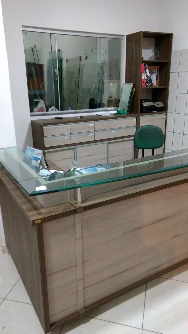 Balcão de recepção comercial em madeira com tampo de vidro, feito pela MENCA Móveis